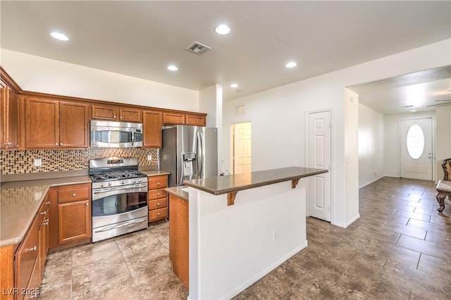 kitchen with visible vents, a kitchen bar, backsplash, a kitchen island, and appliances with stainless steel finishes