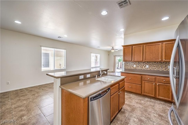 kitchen with brown cabinetry, decorative backsplash, stainless steel appliances, and a sink