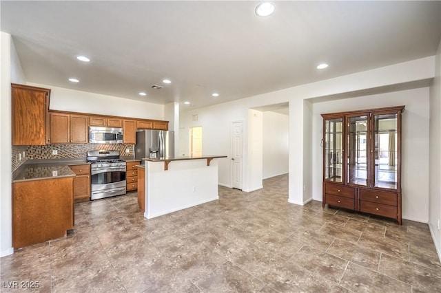 kitchen with a center island, brown cabinetry, a breakfast bar, stainless steel appliances, and recessed lighting