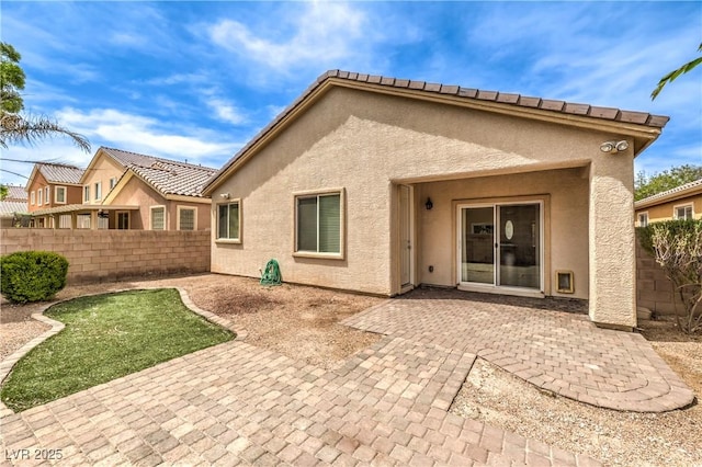 rear view of property featuring stucco siding, a patio area, and a fenced backyard