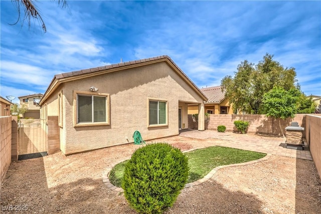 back of house with stucco siding, a patio area, and a fenced backyard