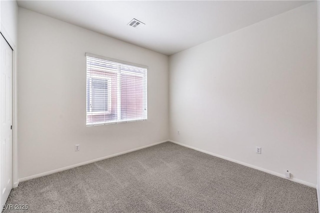 carpeted spare room featuring visible vents and baseboards
