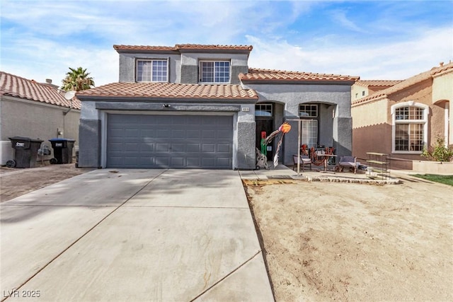 mediterranean / spanish house featuring stucco siding, a tiled roof, and concrete driveway