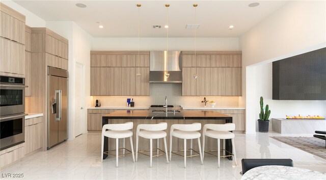 kitchen with modern cabinets, built in refrigerator, wall chimney exhaust hood, and stainless steel double oven