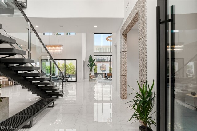 interior space featuring a chandelier, a high ceiling, recessed lighting, and marble finish floor