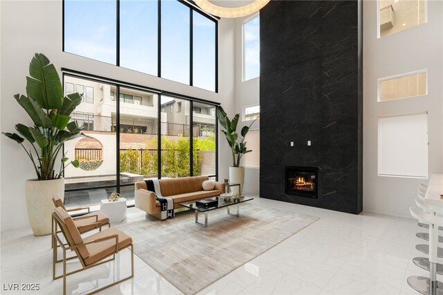 interior space featuring a premium fireplace, marble finish floor, and a towering ceiling