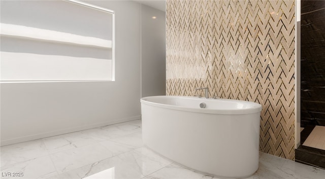 bathroom with a freestanding tub, baseboards, and marble finish floor