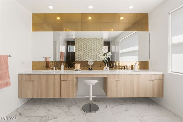 bathroom with marble finish floor, baseboards, a sink, and double vanity