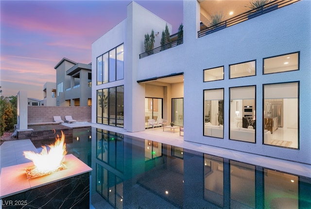 pool at dusk featuring fence, a patio area, an outdoor fire pit, and a fenced in pool