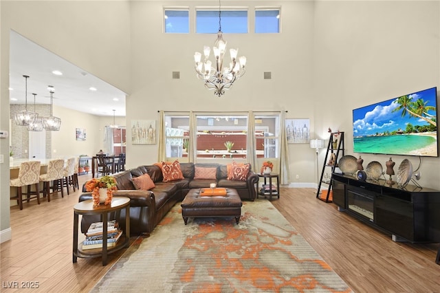 living room featuring a towering ceiling, wood finished floors, and a chandelier
