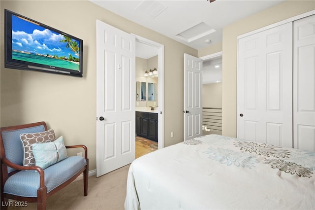 bedroom featuring a sink, ensuite bathroom, a closet, attic access, and light carpet