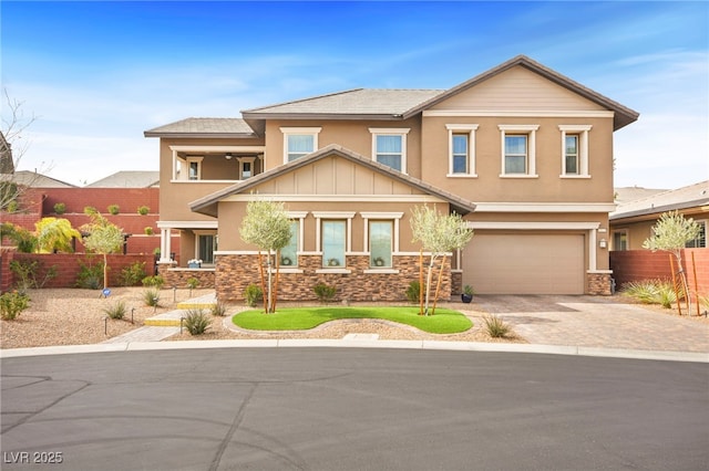 craftsman-style house with stone siding, driveway, fence, and a garage