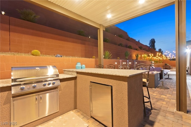 view of patio with an outdoor kitchen, grilling area, a fenced backyard, and outdoor dry bar