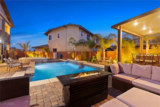 pool at dusk with a fenced in pool, a fenced backyard, an outdoor living space with a fire pit, and a patio