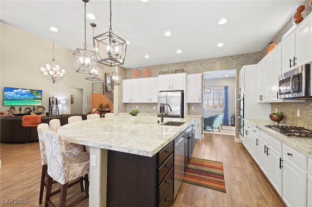 kitchen with white cabinets, stainless steel appliances, a breakfast bar, a sink, and decorative backsplash