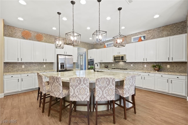 kitchen featuring recessed lighting, stainless steel appliances, backsplash, a sink, and white cabinetry