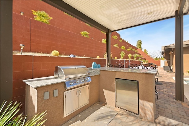 view of patio / terrace featuring fence, an outdoor kitchen, an outdoor bar, and area for grilling