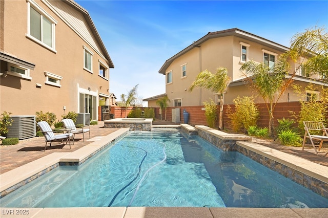 view of swimming pool featuring a pool with connected hot tub, a patio, a fenced backyard, and central AC unit