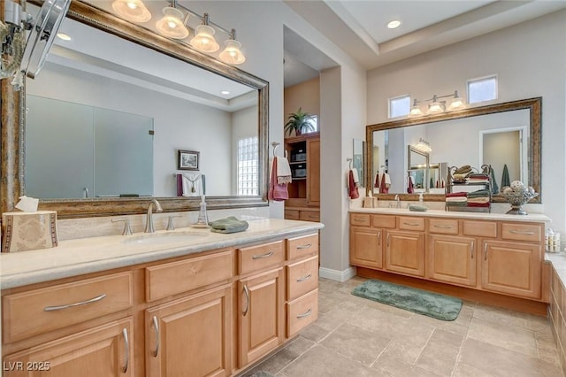 bathroom with two vanities, a tray ceiling, and a sink
