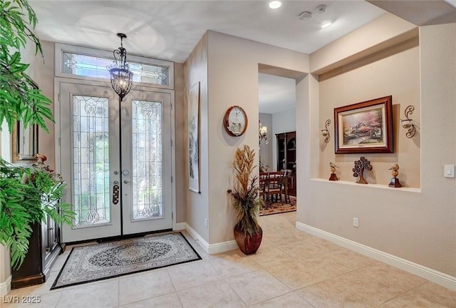 tiled entrance foyer featuring an inviting chandelier, french doors, and baseboards