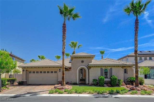 mediterranean / spanish-style home featuring stucco siding, an attached garage, driveway, and a front lawn