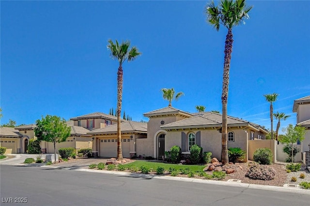 mediterranean / spanish house with a garage, driveway, stucco siding, and fence