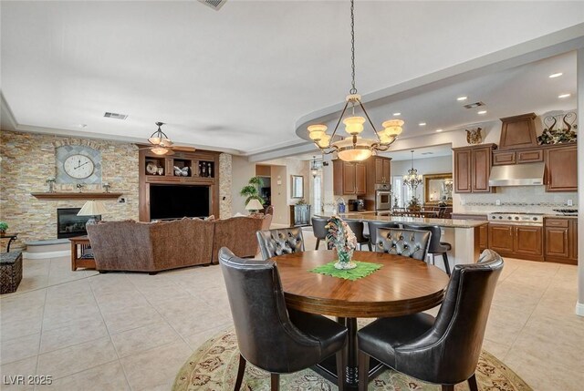 dining area featuring a stone fireplace, light tile patterned flooring, an inviting chandelier, visible vents, and recessed lighting