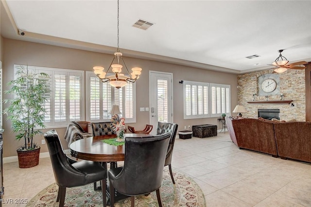 dining area with a stone fireplace, visible vents, a notable chandelier, and light tile patterned floors