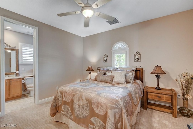 bedroom with ensuite bathroom, ceiling fan, light carpet, baseboards, and visible vents