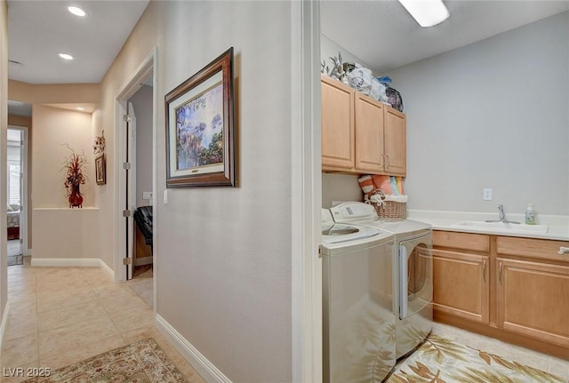 laundry area featuring a sink, light tile patterned floors, cabinet space, washing machine and dryer, and baseboards