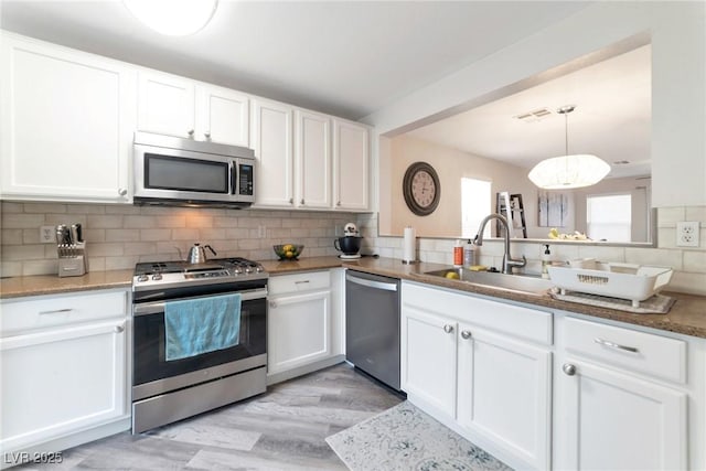 kitchen with white cabinets, stainless steel appliances, visible vents, and a sink