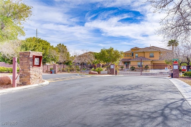 4624 Leon De Oro Dr, Las Vegas, NV 89129 - view of asphalt road featuring a gate, a gated entry, traffic signs, a residential view, and curbs