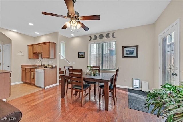 dining area featuring light wood-style floors, plenty of natural light, a ceiling fan, and baseboards