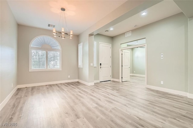 unfurnished room with a chandelier, baseboards, visible vents, and light wood-style floors