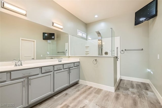 full bathroom featuring double vanity, baseboards, wood finished floors, and a sink