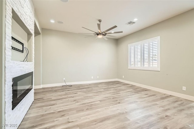 unfurnished living room with visible vents, a fireplace, light wood-style floors, and ceiling fan