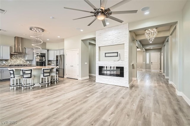 living area with baseboards, ceiling fan with notable chandelier, light wood-type flooring, and recessed lighting