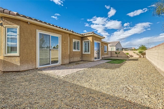 back of house with a patio area, a fenced backyard, a tiled roof, and stucco siding