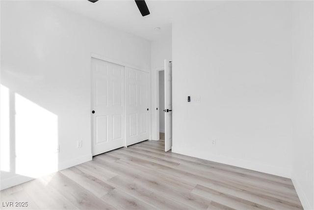 empty room featuring a ceiling fan, baseboards, and light wood-style floors