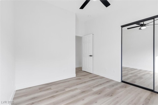unfurnished bedroom with wood finished floors, a closet, a ceiling fan, and baseboards