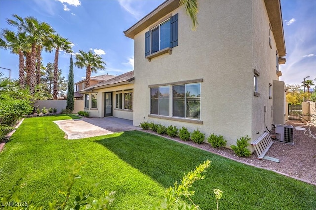 back of house featuring fence, cooling unit, stucco siding, a patio area, and a lawn