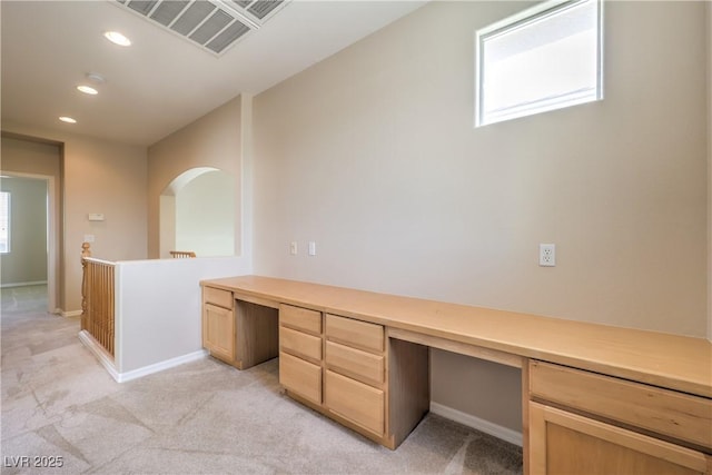unfurnished office featuring baseboards, visible vents, light colored carpet, and built in study area