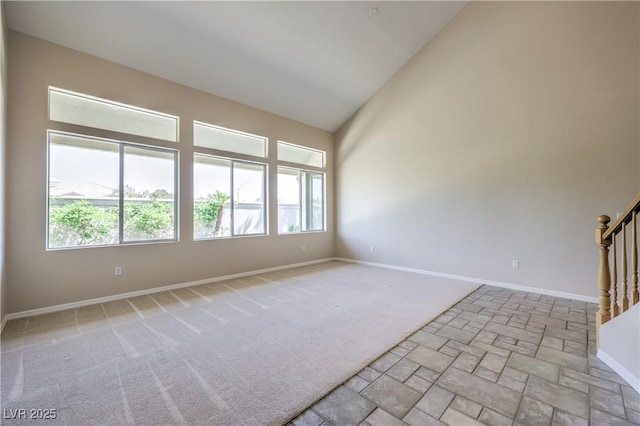carpeted spare room featuring high vaulted ceiling, baseboards, and stairs
