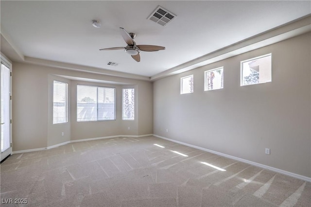 spare room with baseboards, a ceiling fan, visible vents, and light colored carpet