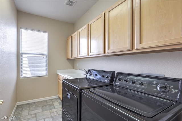washroom featuring a sink, stone finish flooring, baseboards, visible vents, and independent washer and dryer