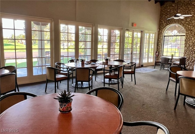 dining room featuring a high ceiling, carpet flooring, and ceiling fan