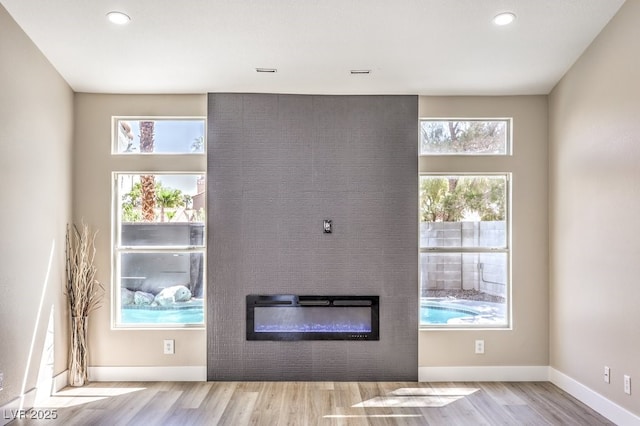 unfurnished living room featuring baseboards, wood finished floors, a fireplace, and recessed lighting