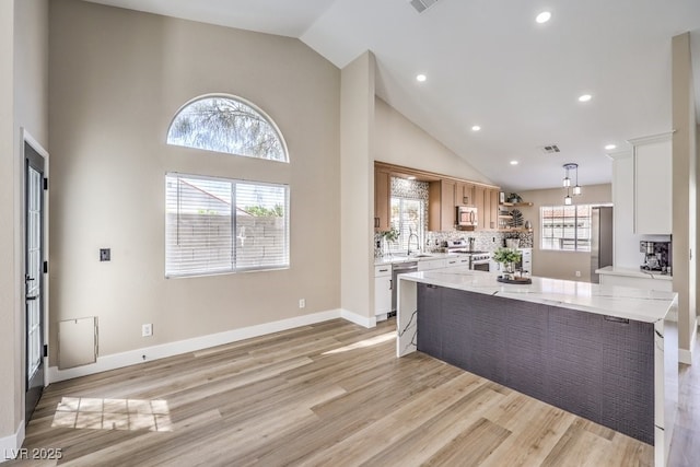 kitchen featuring a center island, light wood-style floors, open shelves, high vaulted ceiling, and appliances with stainless steel finishes