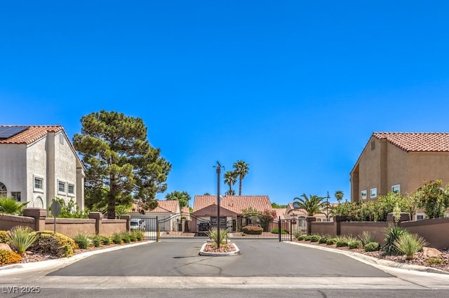 view of street featuring a gate, a residential view, a gated entry, and curbs