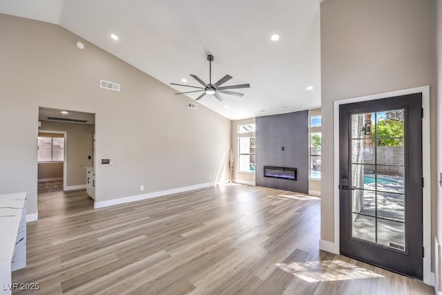 unfurnished living room with high vaulted ceiling, ceiling fan, visible vents, and plenty of natural light